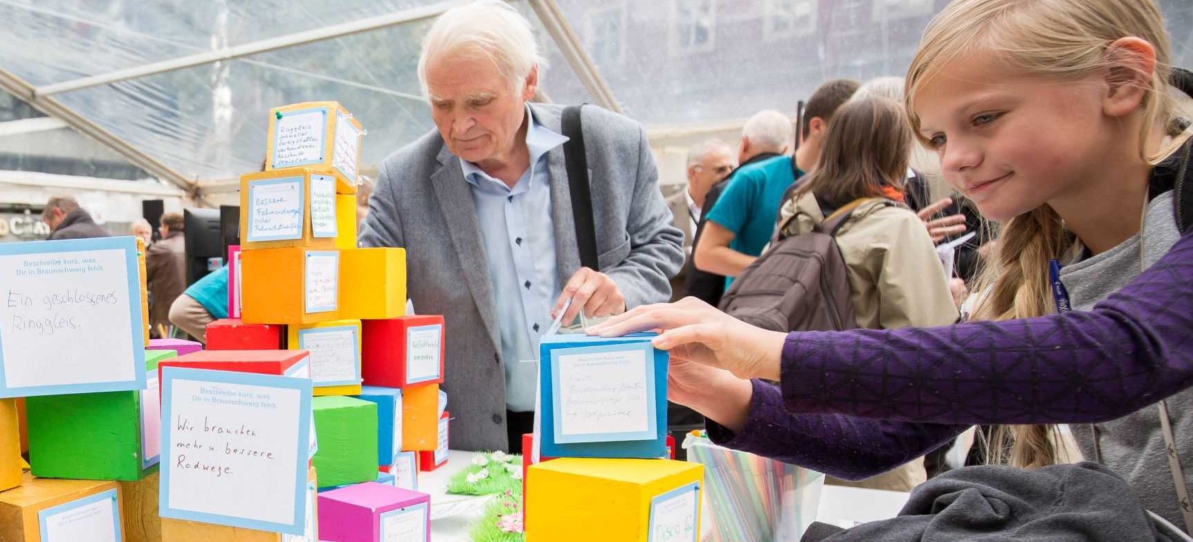 Menschen heften ihre Ideen zur Stadtentwicklung an bunte Bausteine